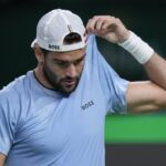 Matteo Berrettini con cappellino e mentre solleva la maglietta all'altezza di una spalla