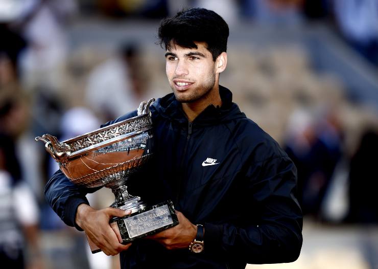 Carlos Alcaraz sorridente con il trofeo del Roland Garros in braccio
