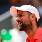 Primo piano di Novak Djokovic con un cappello bianco