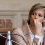 Federica Pellegrini in primo piano, seduta, con una mano sulla bocca e che guarda di lato