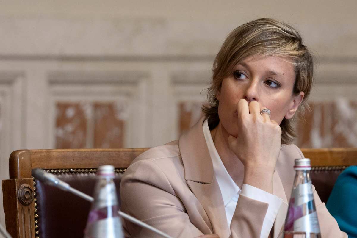 Federica Pellegrini in primo piano, seduta, con una mano sulla bocca e che guarda di lato