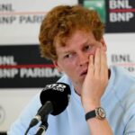 Jannik Sinner, in conferenza stampa, con una mano su una guancia e volto preoccupato