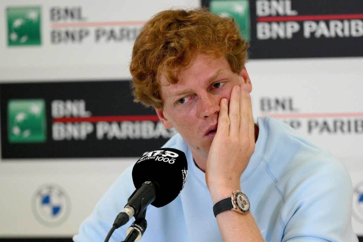 Jannik Sinner, in conferenza stampa, con una mano su una guancia e volto preoccupato