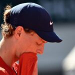 Primo piani di Jannik Sinner con lo sguardo basso e la maglietta in bocca