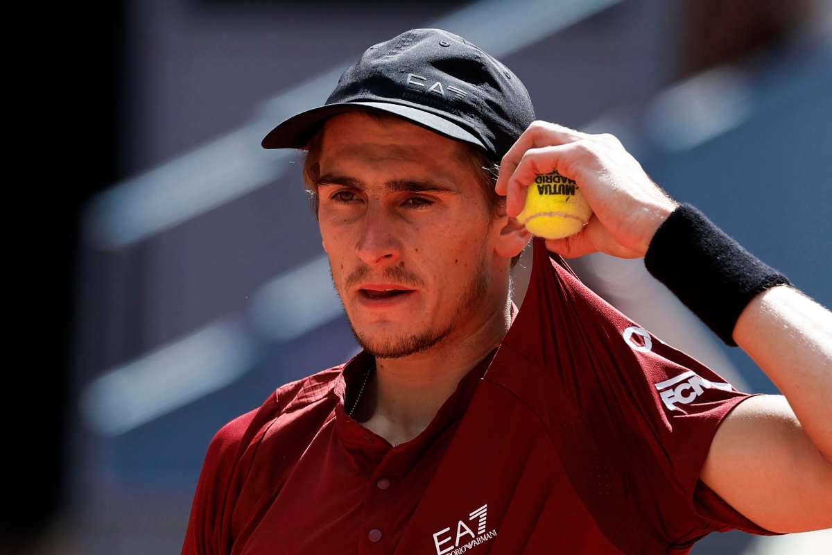 Matteo Arnaldi si aggiusta la maglietta tenendo in mano una pallina