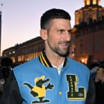 Novak Djokovic sorridente, che indossa una giacca azzurra, nera e gialla