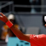 Profilo di Novak Djokovic che si appresta alla battuta lanciando la pallina