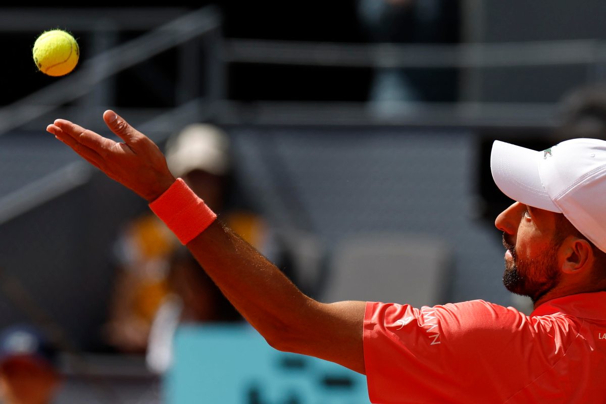 Profilo di Novak Djokovic che si appresta alla battuta lanciando la pallina