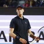 Jannik Sinner con una racchetta in mano e uno sguardo perplesso