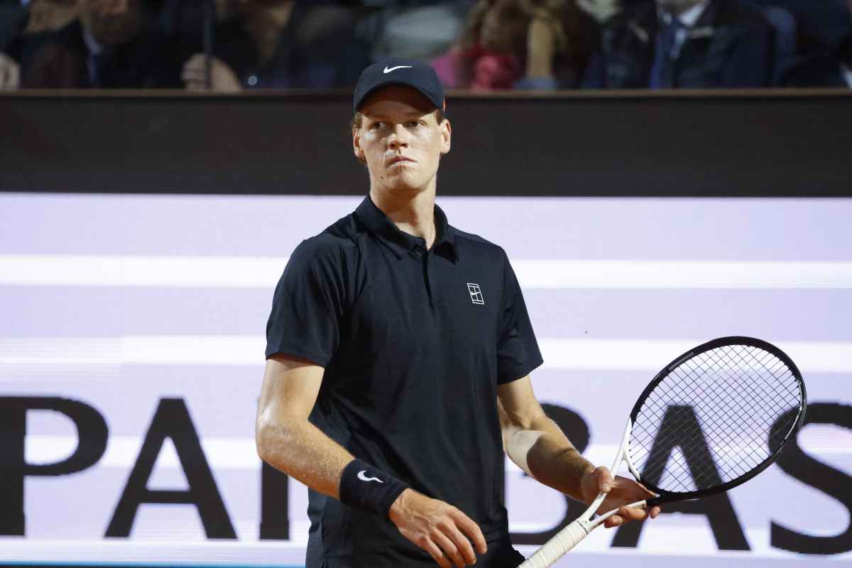 Jannik Sinner con una racchetta in mano e uno sguardo perplesso