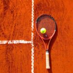Racchetta e pallina sul campo in terra rossa