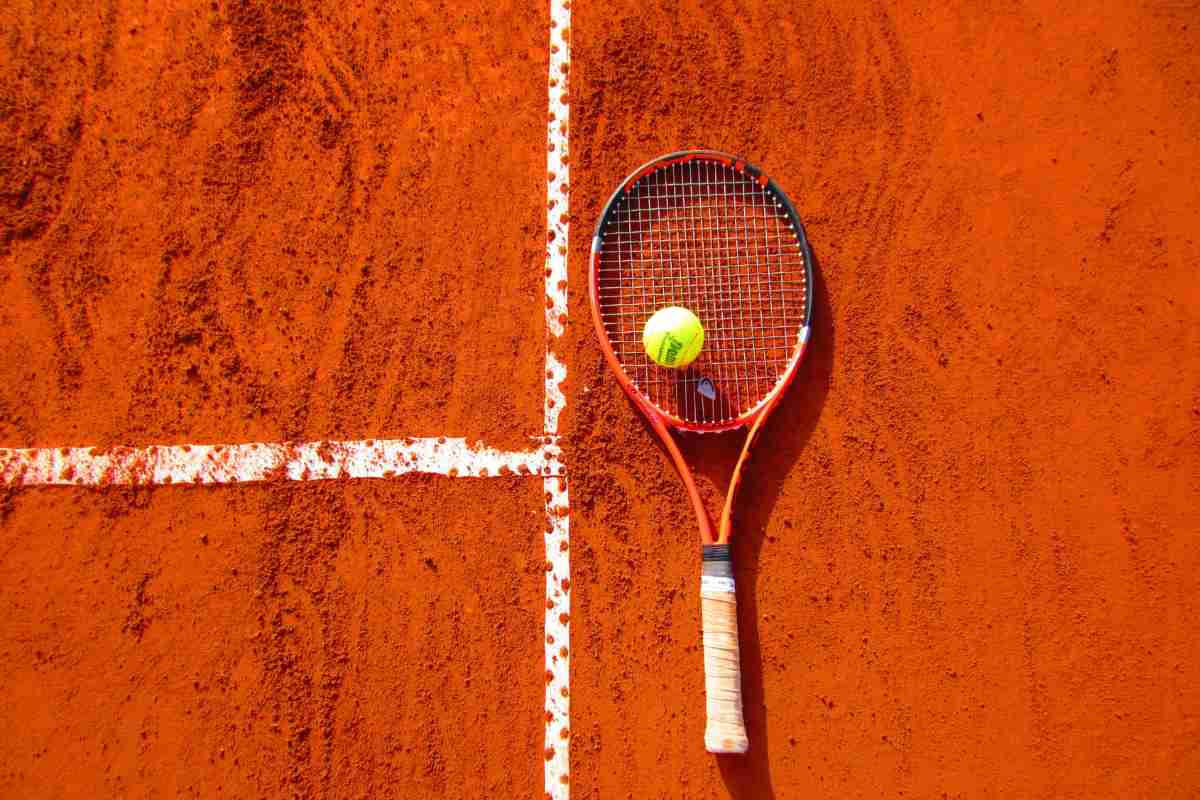 Racchetta e pallina sul campo in terra rossa