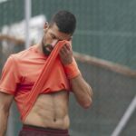 Novak Djokovic si copre il volto con la maglia