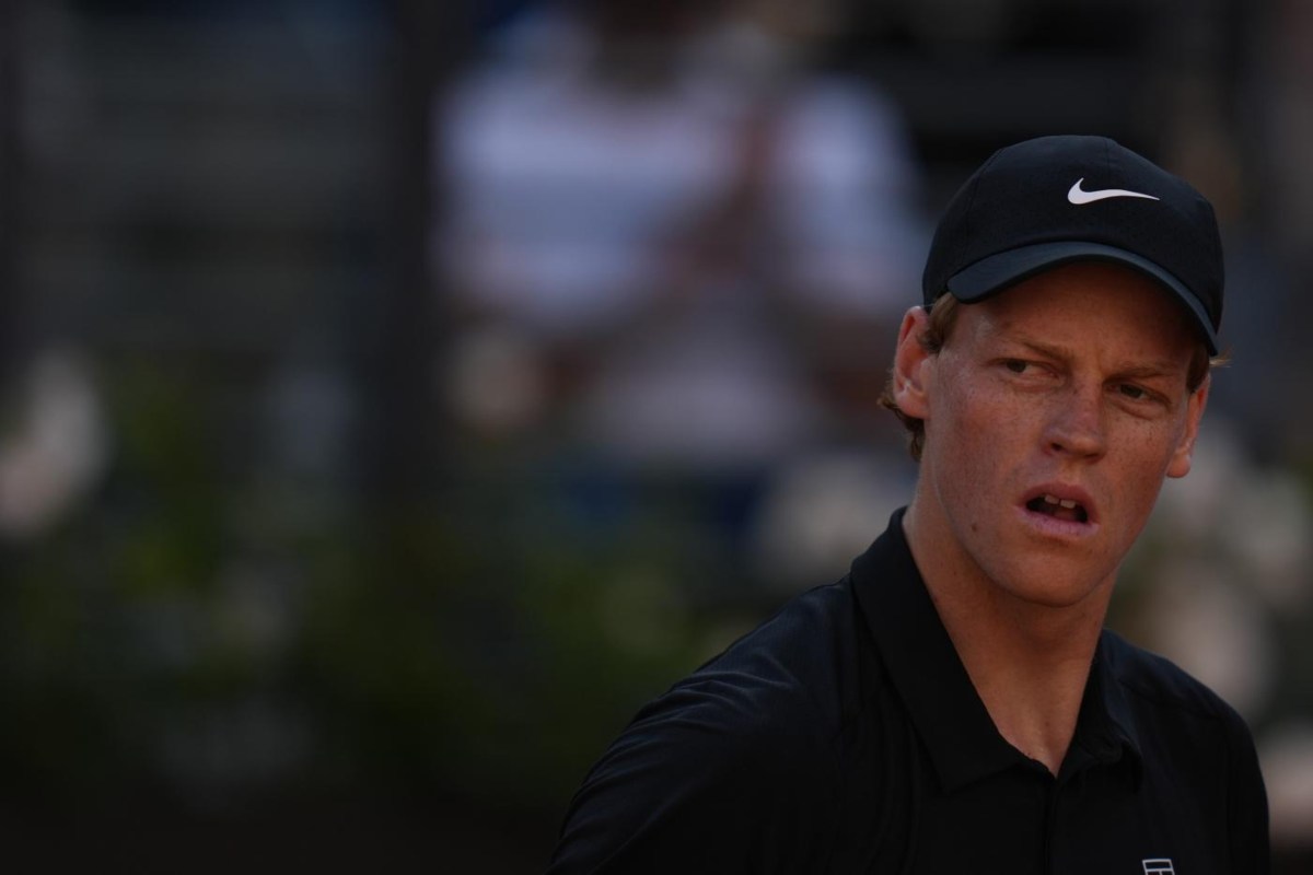 Jannik Sinner in primo piano, con sguardo di lato ed espressione di sorpresa