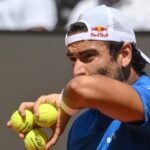 Matteo Berrettini si asciuga il sudore con il polsino, mentre tra la mano stringe tre palline da tennis