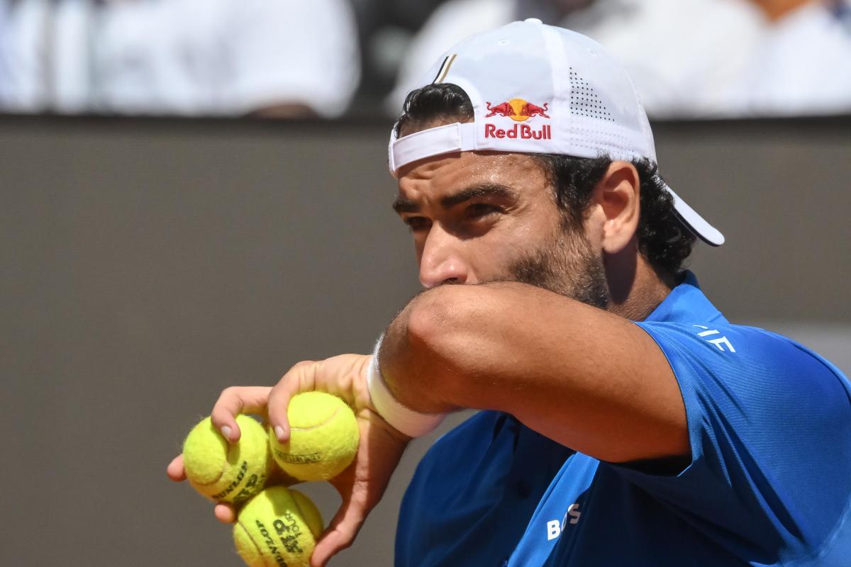 Matteo Berrettini si asciuga il sudore con il polsino, mentre tra la mano stringe tre palline da tennis