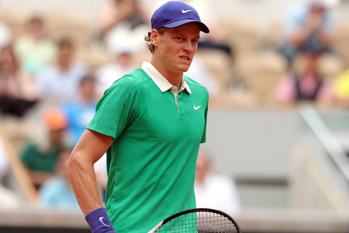 Jannik Sinner con una maglia verde e un cappello blu