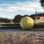 Una pallina da tennis con la racchetta a terra