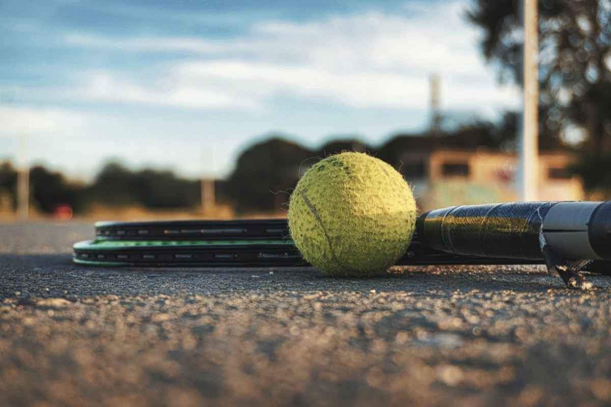 Una pallina da tennis con la racchetta a terra