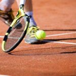 Racchetta e pallina da tennis che rimbalza sulla terra rossa