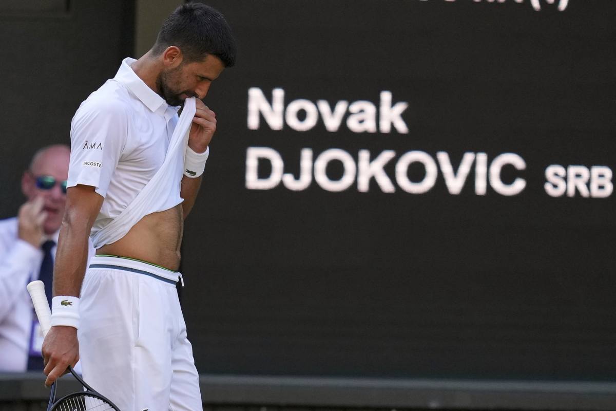 Novak Djokovic di profilo, a capo chino e con un lembo di t-shirt sulle labbra