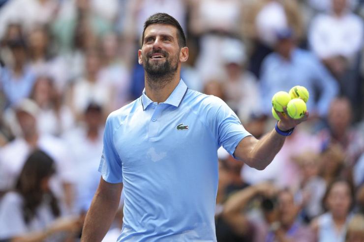 Novak Djokovic sorridente e con in una mano 4 palline