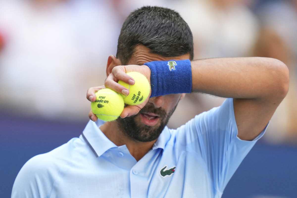 Novak Djokovic in primo piano e con una mano sulla fronte che gli copre parzialmente il viso