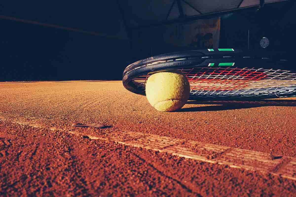 Racchetta e pallina da tennis su un campo in terra rossa