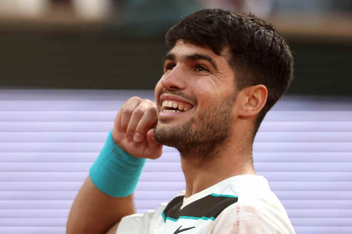 Carlos Alcaraz sorride e si porta il dito all'orecchio