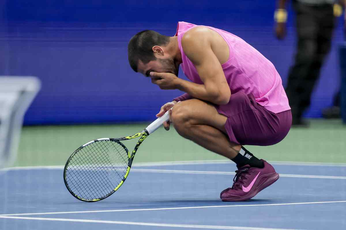 Carlos Alcaraz accovacciato in campo con le mani sul volto