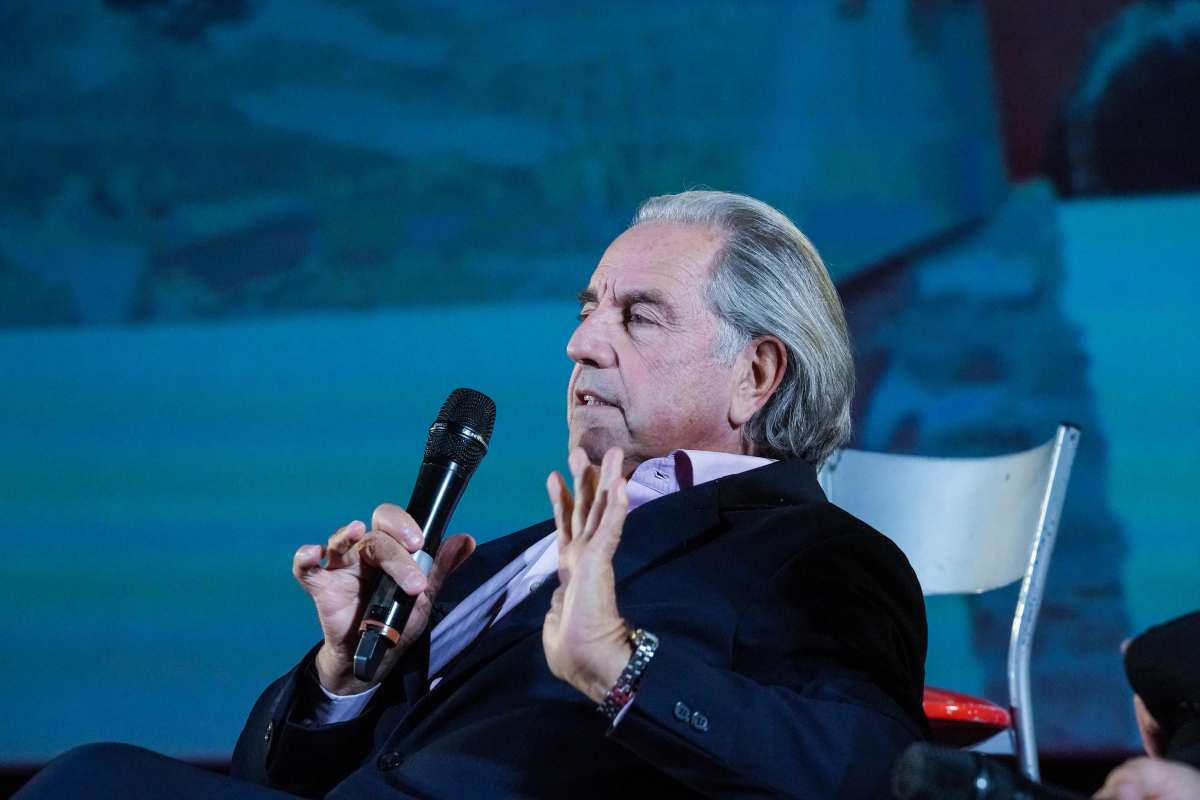 Paolo Bertolucci parla gesticolando con in mano un microfono