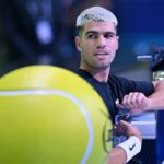 Carlos Alcaraz apre una bottiglina d'acqua mentre è seduto in panchina durante un allenamento alle Finals di Torino