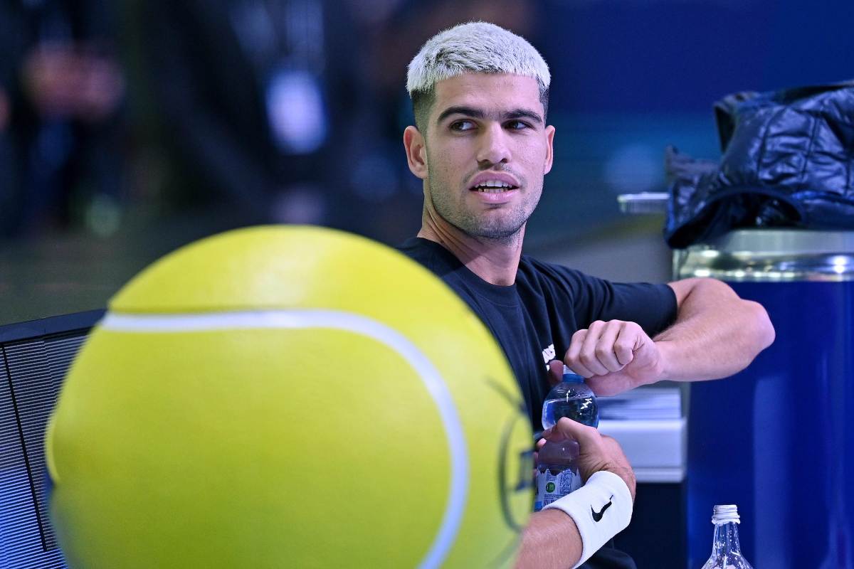 Carlos Alcaraz apre una bottiglina d'acqua mentre è seduto in panchina durante un allenamento alle Finals di Torino