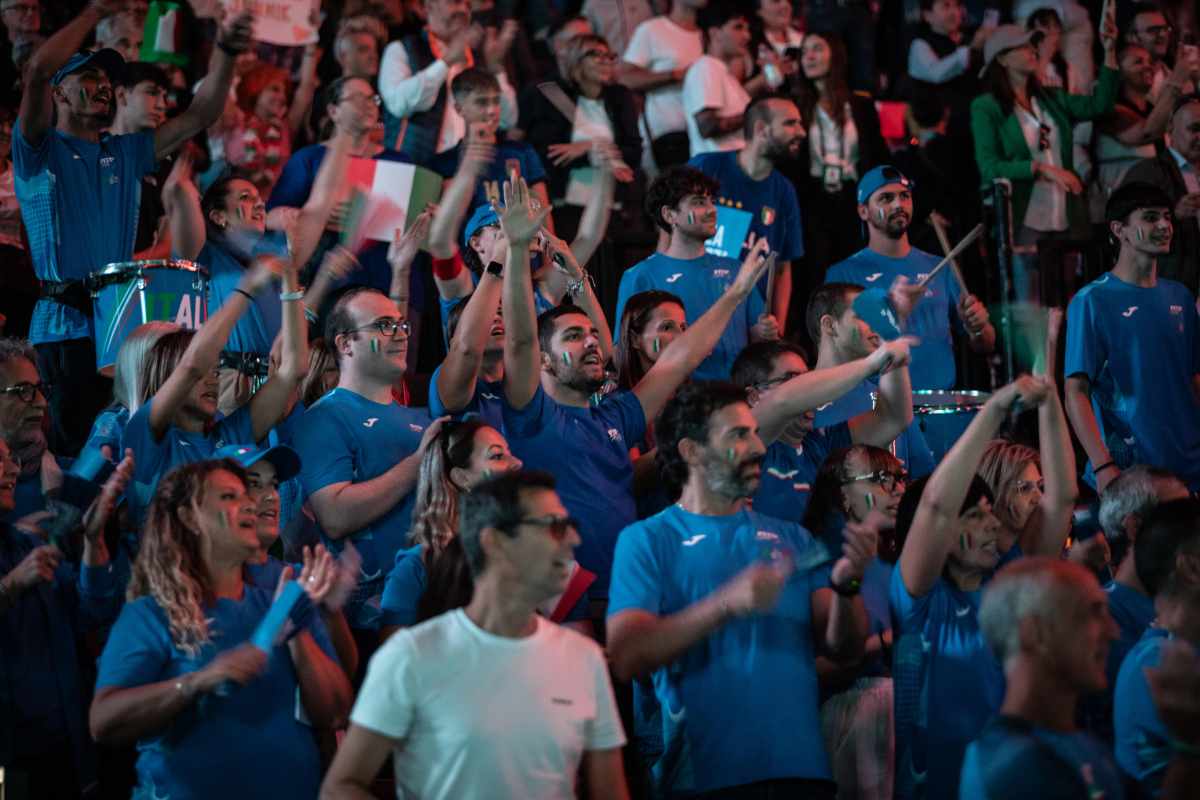Tifosi italiani vestiti d'azzurro sbandierano il tricolore ed alzano le mani al cielo