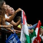 Tifose italiane esultano urlando e sventolando la bandiera tricolore