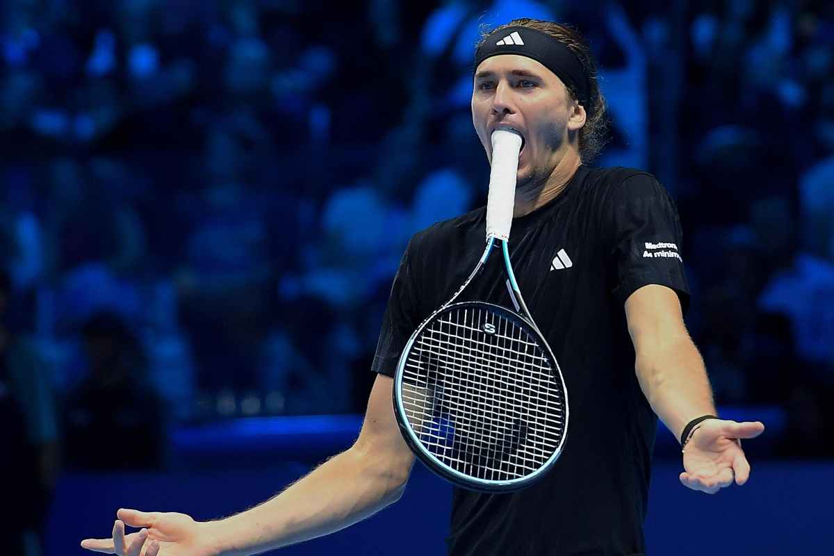 Zverev allarga le braccia sconsolato mentre morde il manico della racchetta