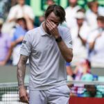 Bublik, vestito di bianco, si porta la mano sinistra al volto