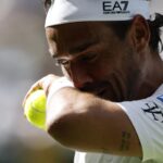Primo piano di Fognini che si asciuga il sudore al volto con un polsino tenendo un pallina stretta nella mano