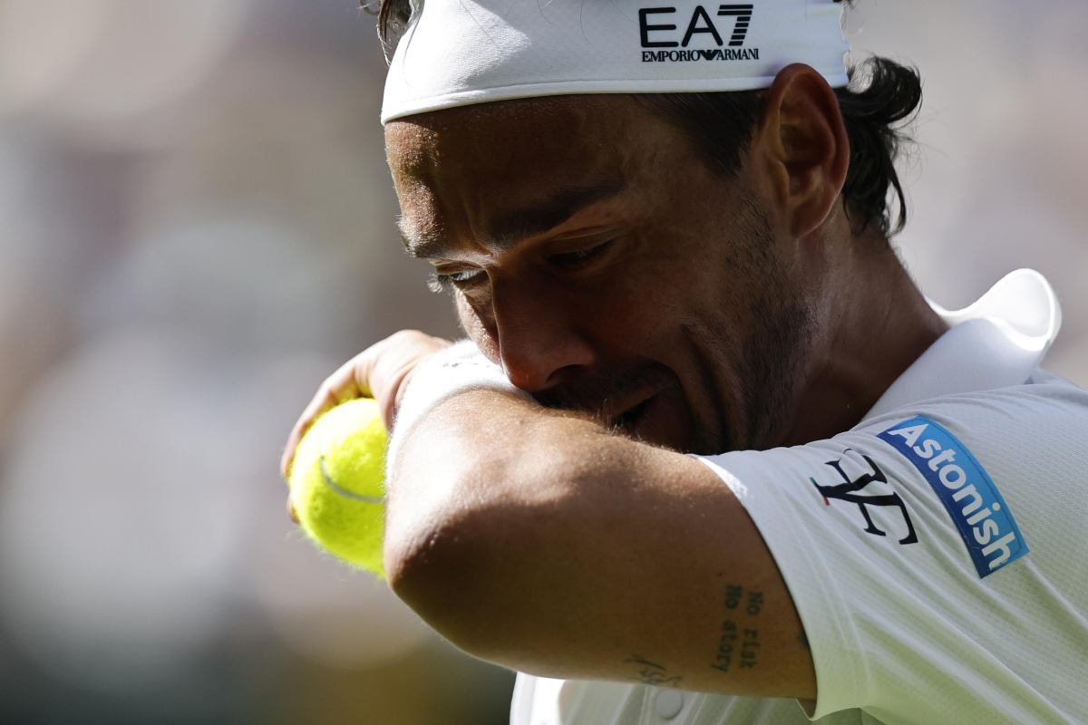 Primo piano di Fognini che si asciuga il sudore al volto con un polsino tenendo un pallina stretta nella mano